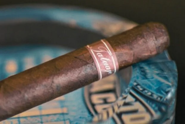 A cigar resting on a blue pack of chewing tobacco.
