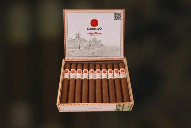 An open box of 13 Carrillo New Wave cigars with a printed interior lid showing a landscape and a palm tree.