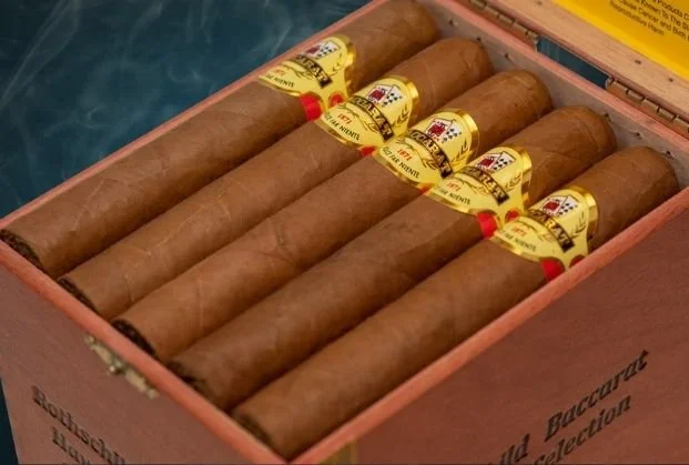 A wooden box containing six cigars with yellow and red bands.