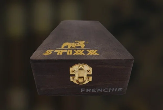 A wooden box with a gold latch, labeled 'FRENCHIE' on the front, with a logo of a rolling pin and the word 'STIXX' on the top surface.