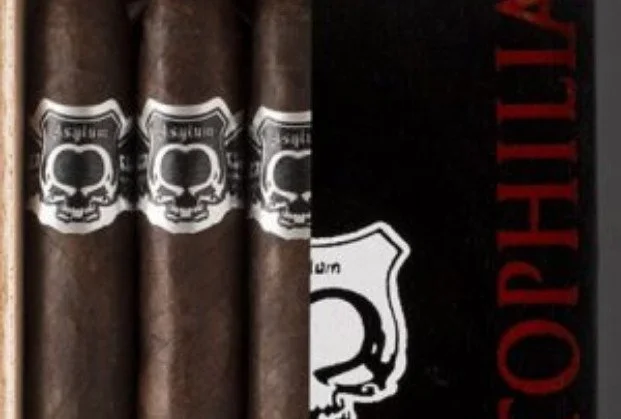 Close-up of cigars with a black and white skull and crossbones label, partially visible box with red and white lettering.