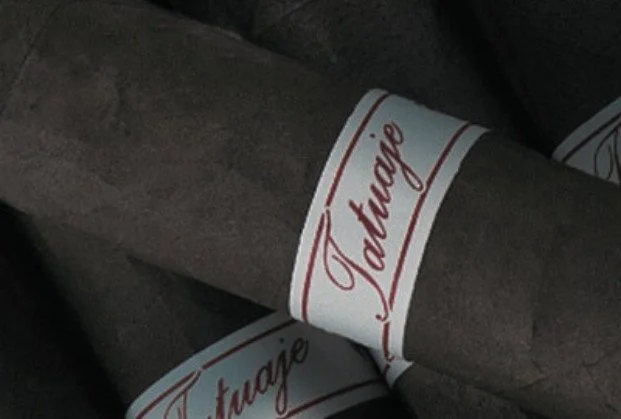 Close-up of two cigars with white bands marked 'Jacarj' in red cursive lettering.