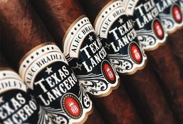 Several cigars with black, white, and red labels that say "Texas Lancer" and "Alec Bradley."