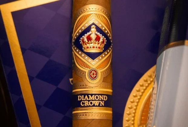 Close-up of a cigar with a gold and blue band featuring a crown, labeled 'Diamond Crown'.