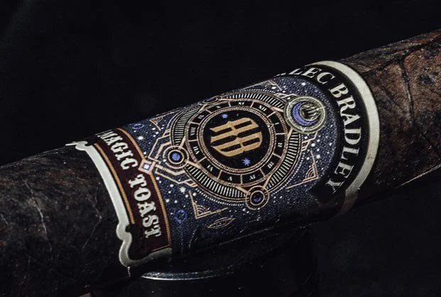 Close-up of a cigar with a dark band featuring gold and silver details, stars, and the words "LE CIGAR BRADLE" and "FESTA.