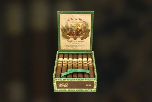 Open green cigar box containing ten cigars with gold bands, labeled 'Cameroon Selection' and 'Toro'.