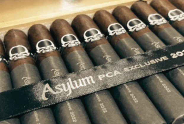 A row of cigars with a black band labeled 'Asylum PCA Exclusive 202'.