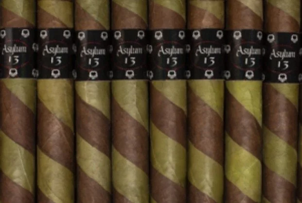Multiple cigars with black and gold labels, featuring the brand name 'Asylum 13', arranged in two rows.