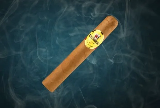 A cigar with a yellow label, floating above a dark blue background with wisps of smoke.