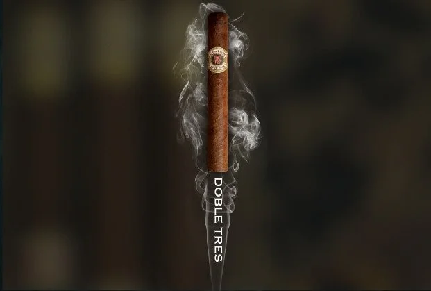 A lit cigar with smoke rising, mounted on a golf tee with the text 'Dobbie Ties' on it, against a dark background.