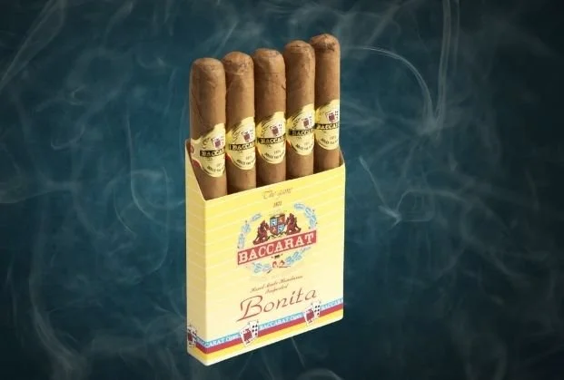 A pack of six cigars in a yellow pack labeled Bacharati Bonita, placed on a dark surface with smoke in the background.