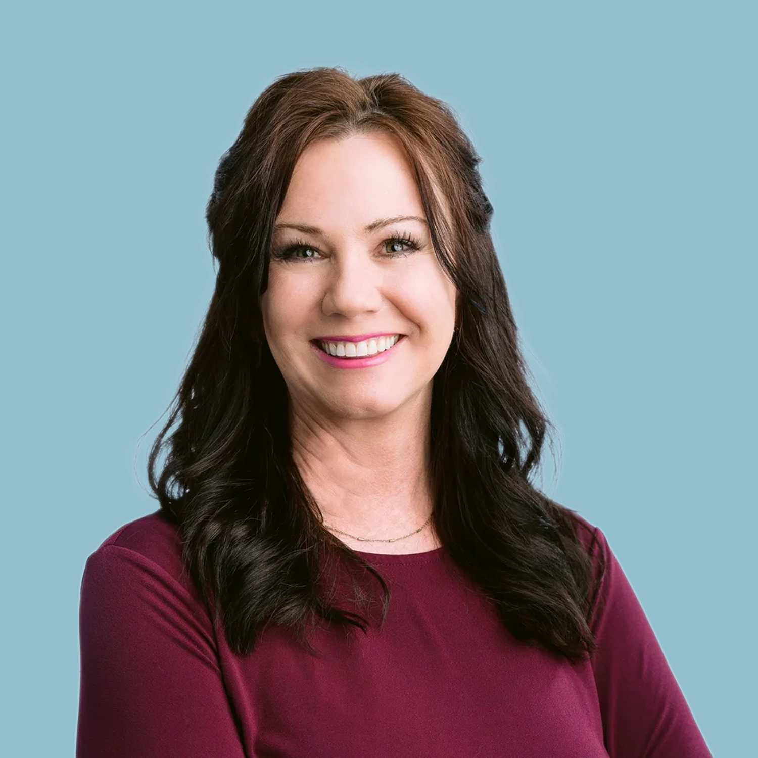 A photo of a woman smiling with dark hair and a maroon shirt.