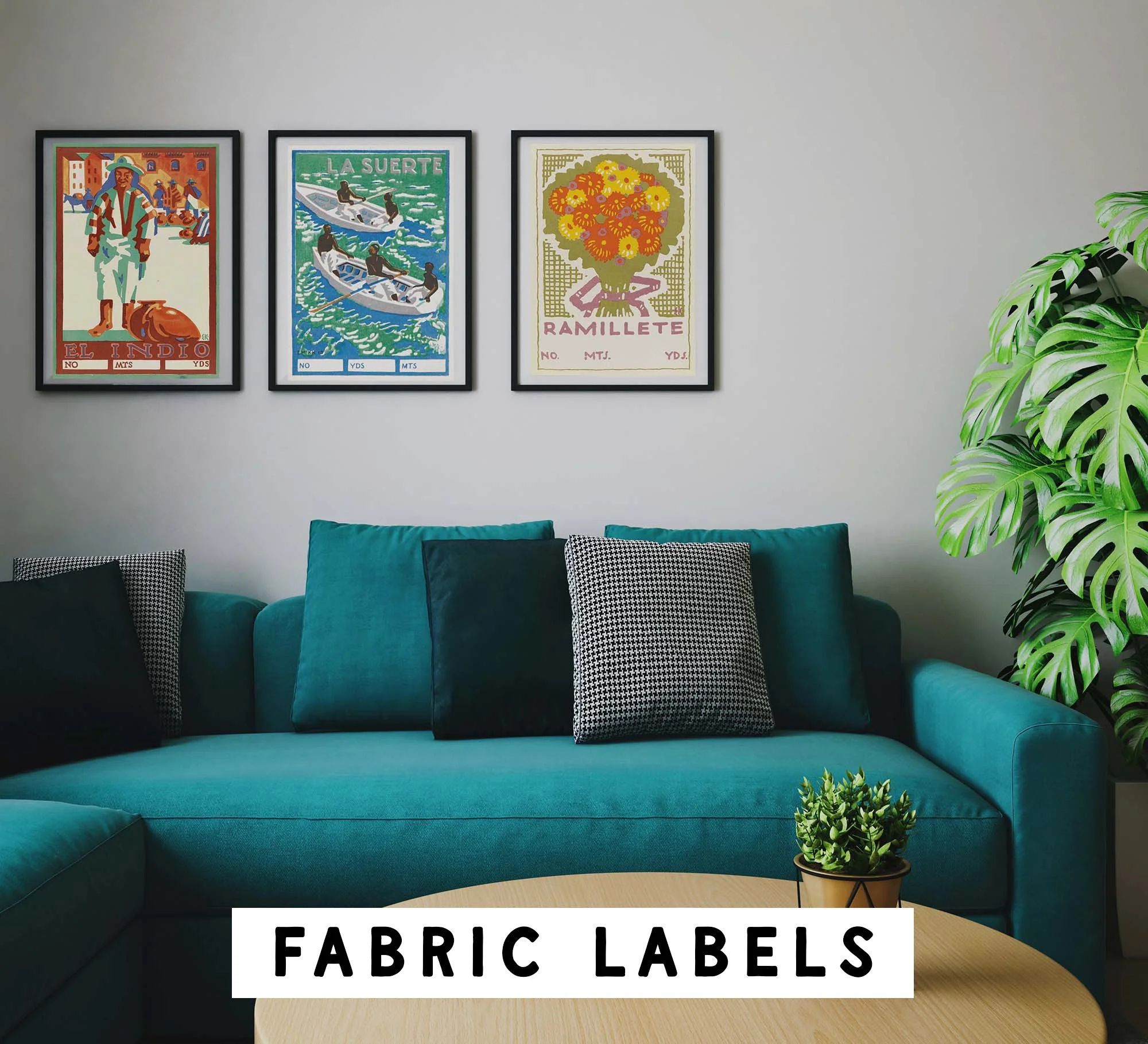 A teal sofa with black and white patterned pillows, a potted plant on a small table, and three framed art prints of vintage-style posters on the wall behind the sofa. The posters feature colorful illustrations and text, including "El Indio," "La Suerte," and "Ramillete." The bottom of the image contains text reading "FABRIC LABELS."