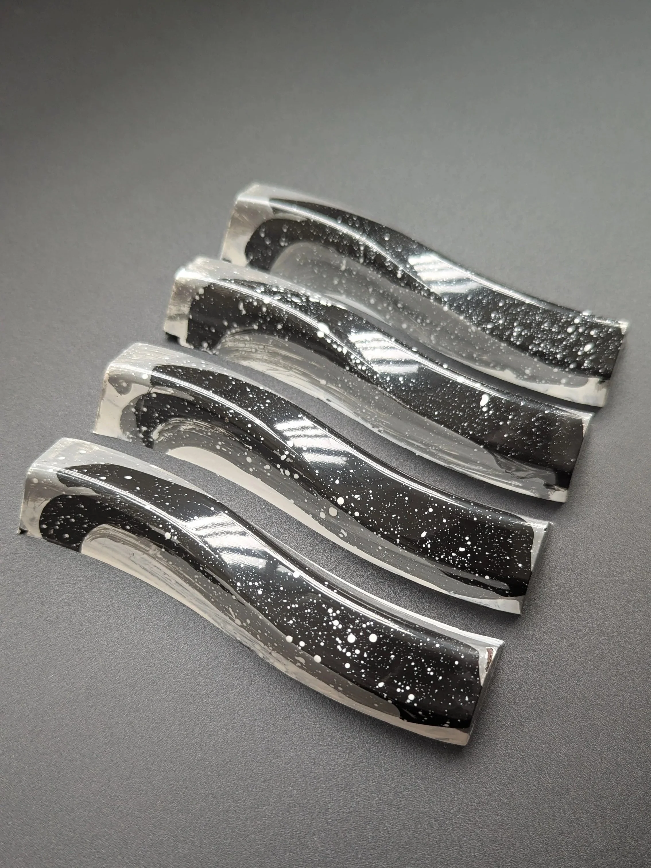 Four chocolate bars with black and white speckled design on a gray surface.