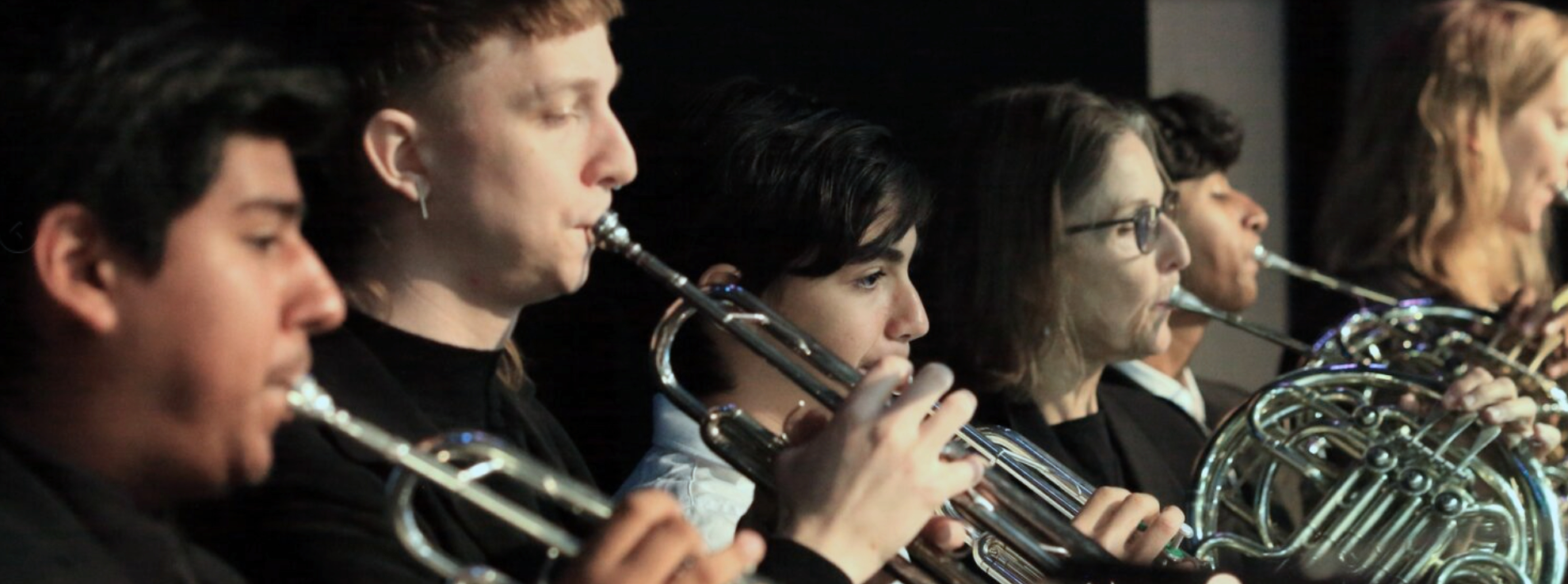 Young musicians playing French horns in an orchestra.