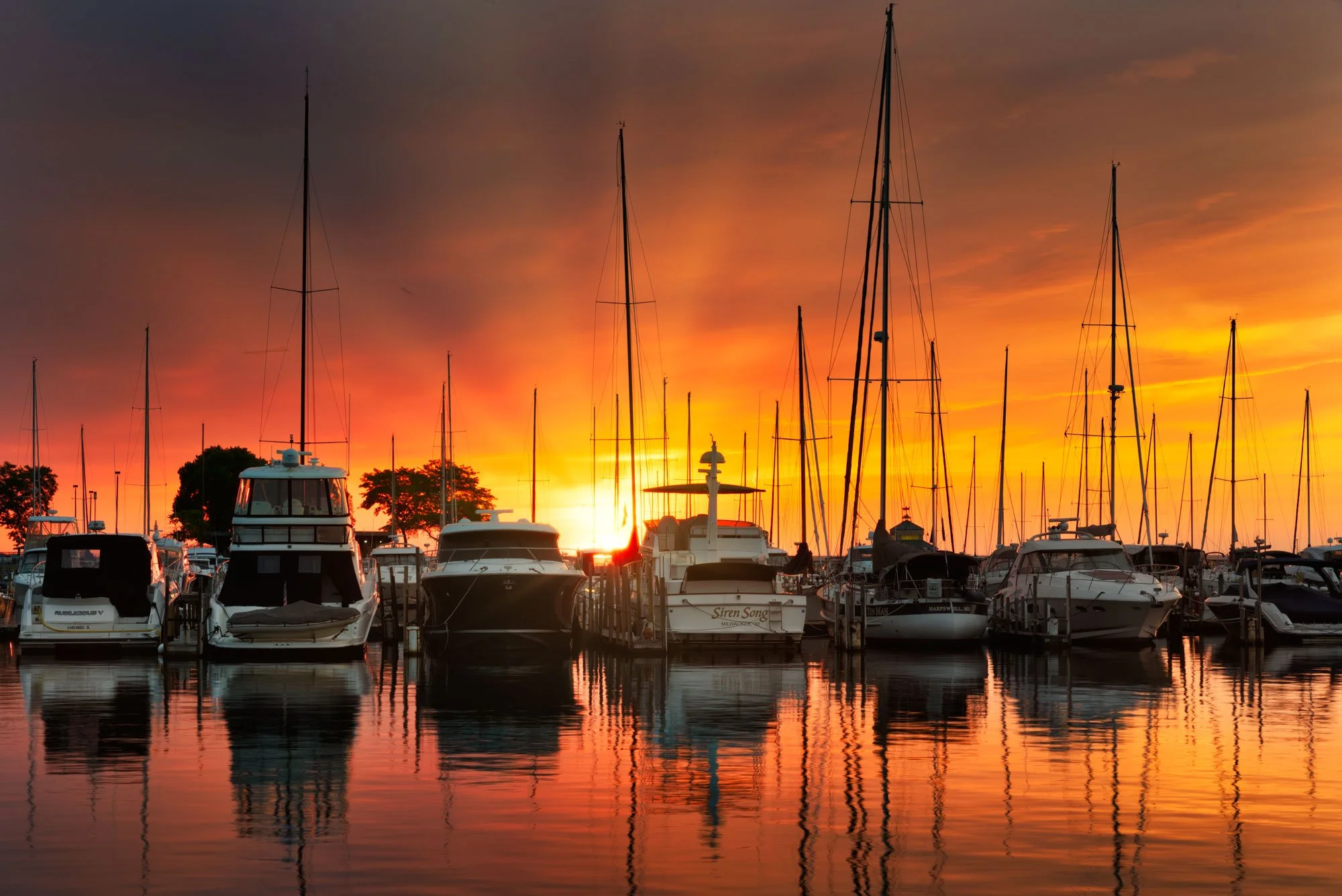 Yacht marina at sunset with boats and water reflecting the sky