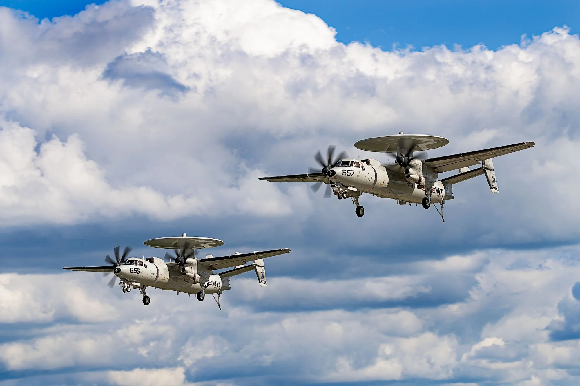 Two military aircraft flying in formation against a cloudy sky.