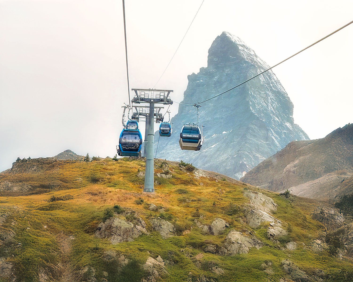 Cable cars traveling over a mountain landscape with a large peak in the background.
