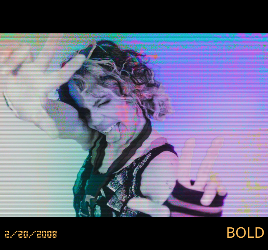 A person with curly hair making a peace sign and smiling wearing a dark shirt with patterned details, standing against a colorful, glitchy background.