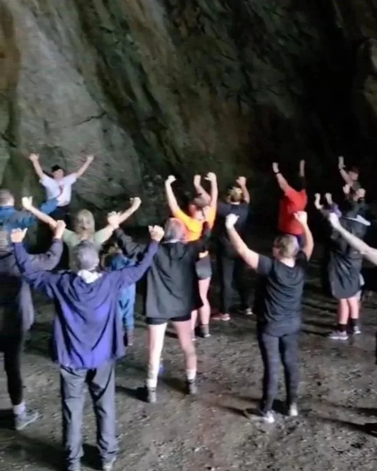 Yoga Class inside a cave, raising their arms in celebration or triumph.