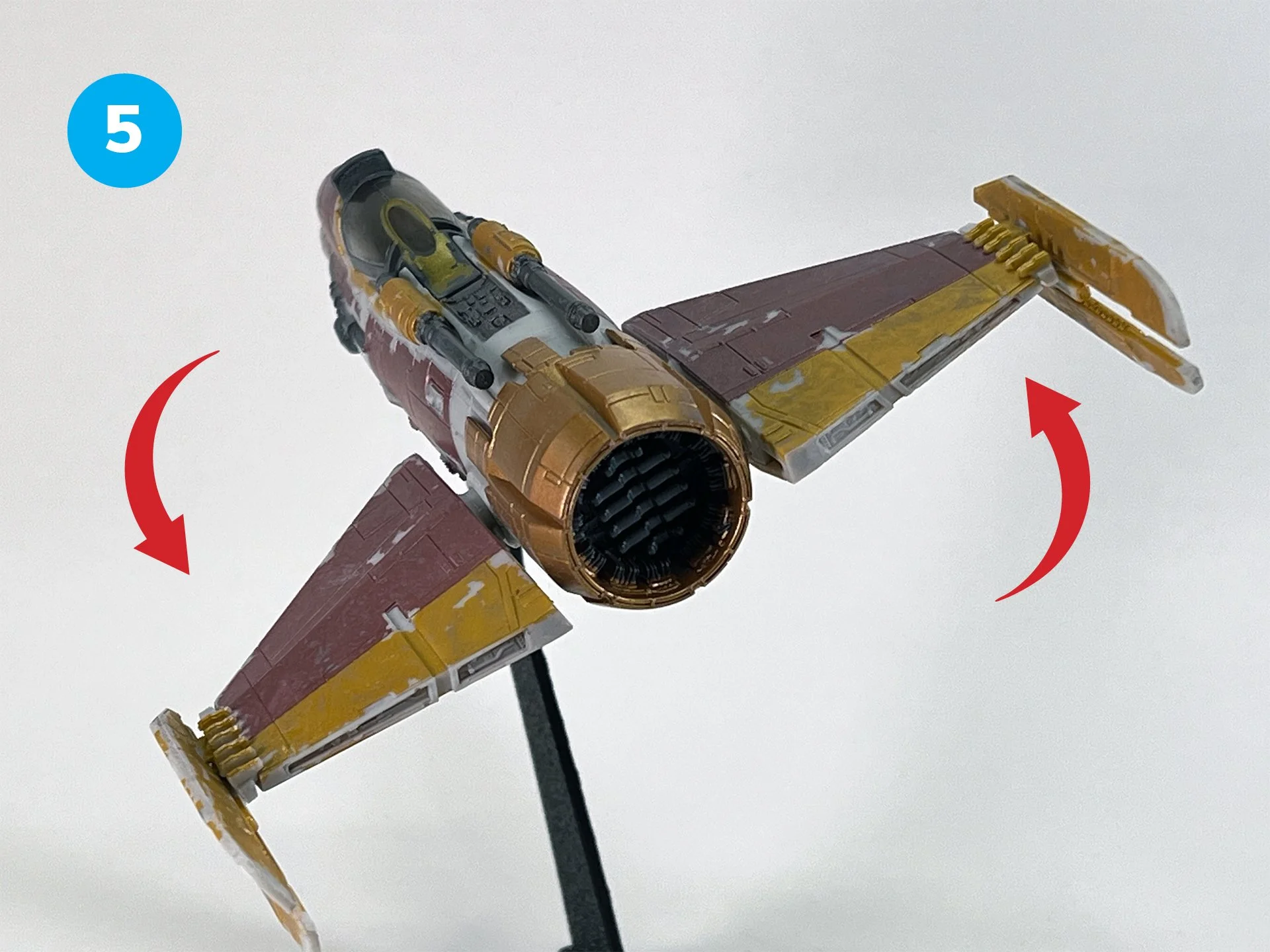Toy spaceship with adjustable wings, mounted on a stand, facing downward.