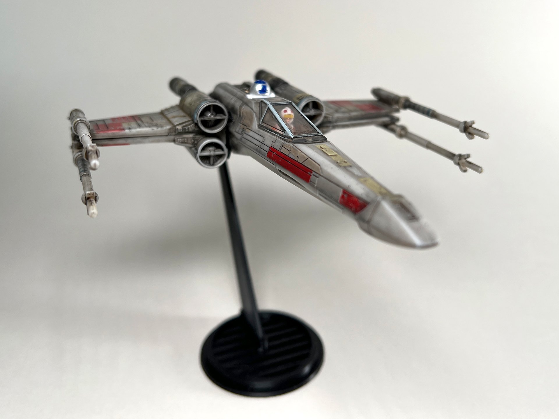 A detailed model of the X-Wing Flight Stand (Closed Wings) from Star Wars, displayed on a black stand against a plain white background.