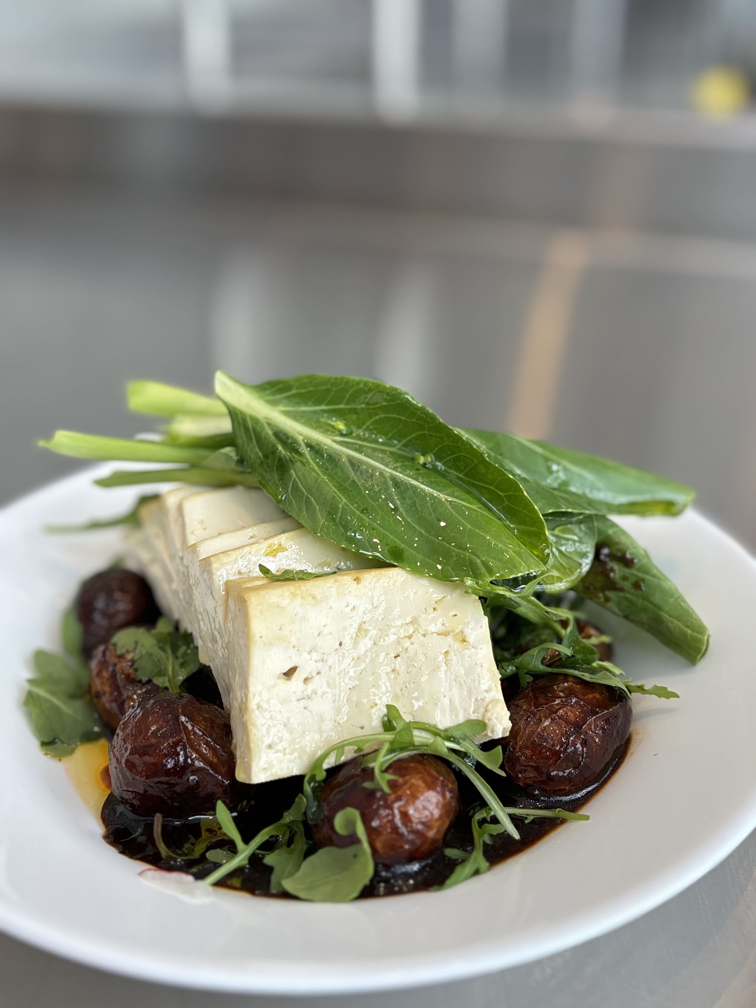 Plat avec du fromage blanc, feuilles de basilic, microgreens, dattes et sauce