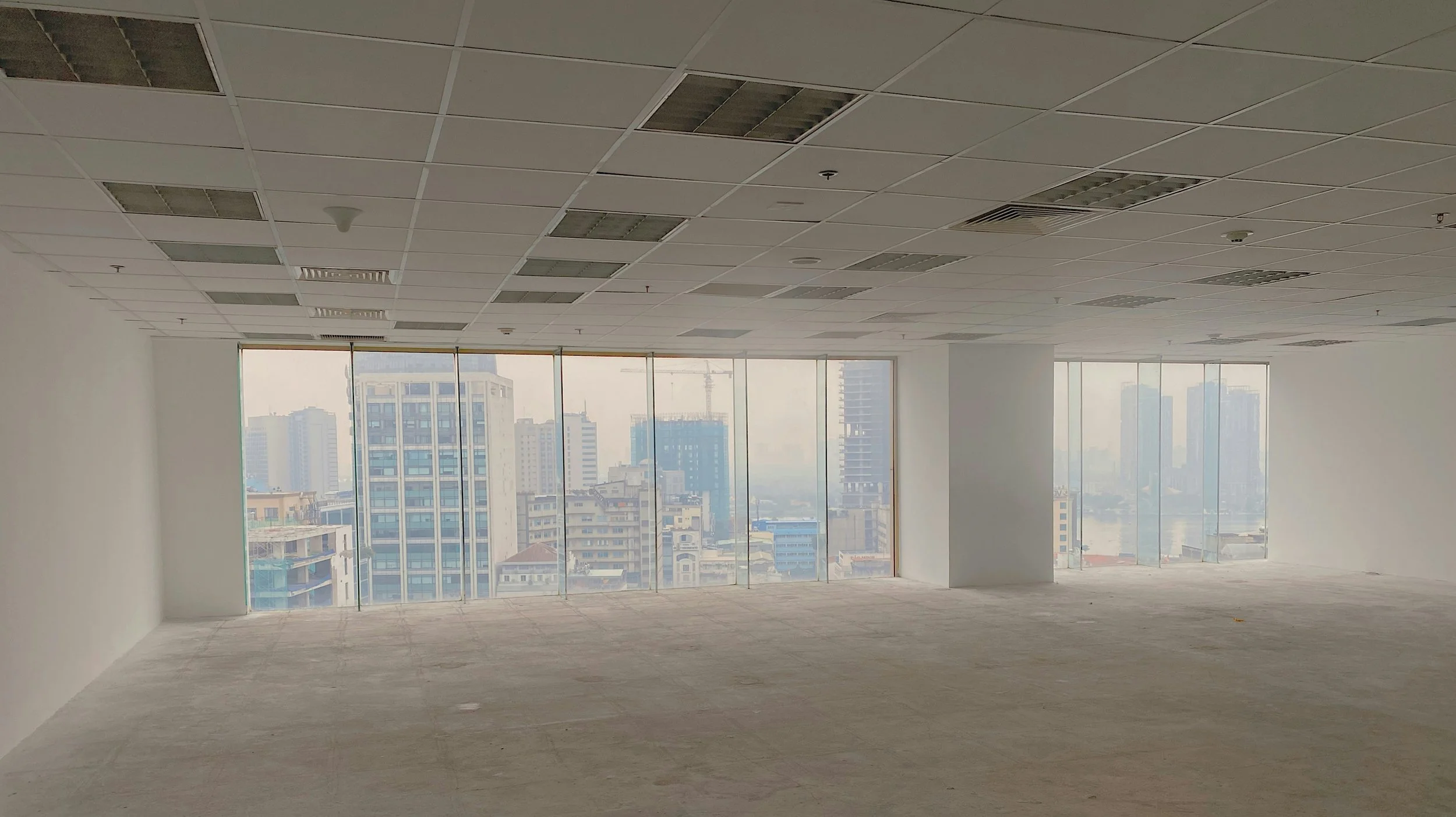 Empty office space with large windows showing a city skyline with high-rise buildings.