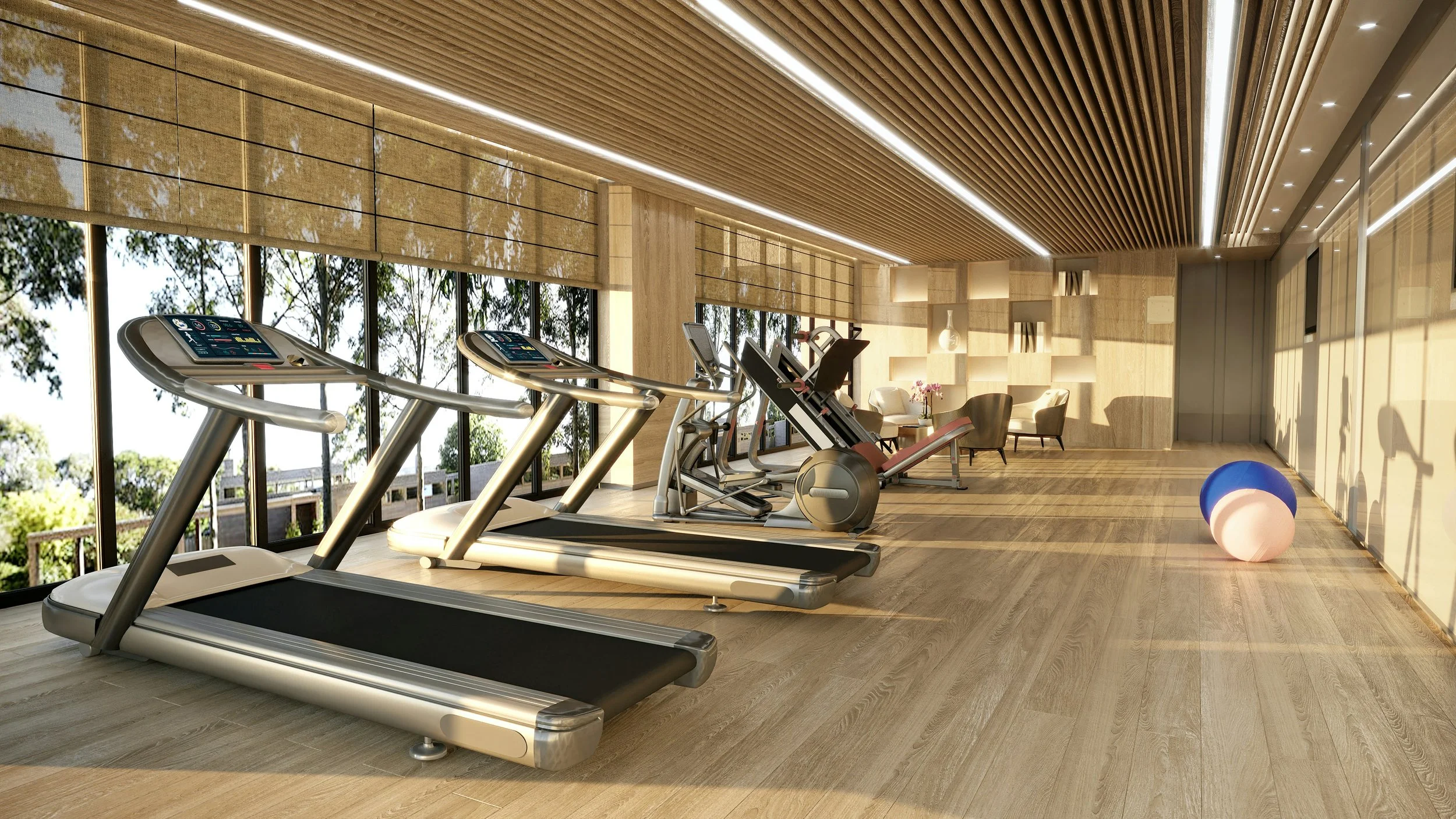 Modern gym with treadmills, elliptical machines, and a sitting area with chairs and shelves, illuminated by natural light through large windows.