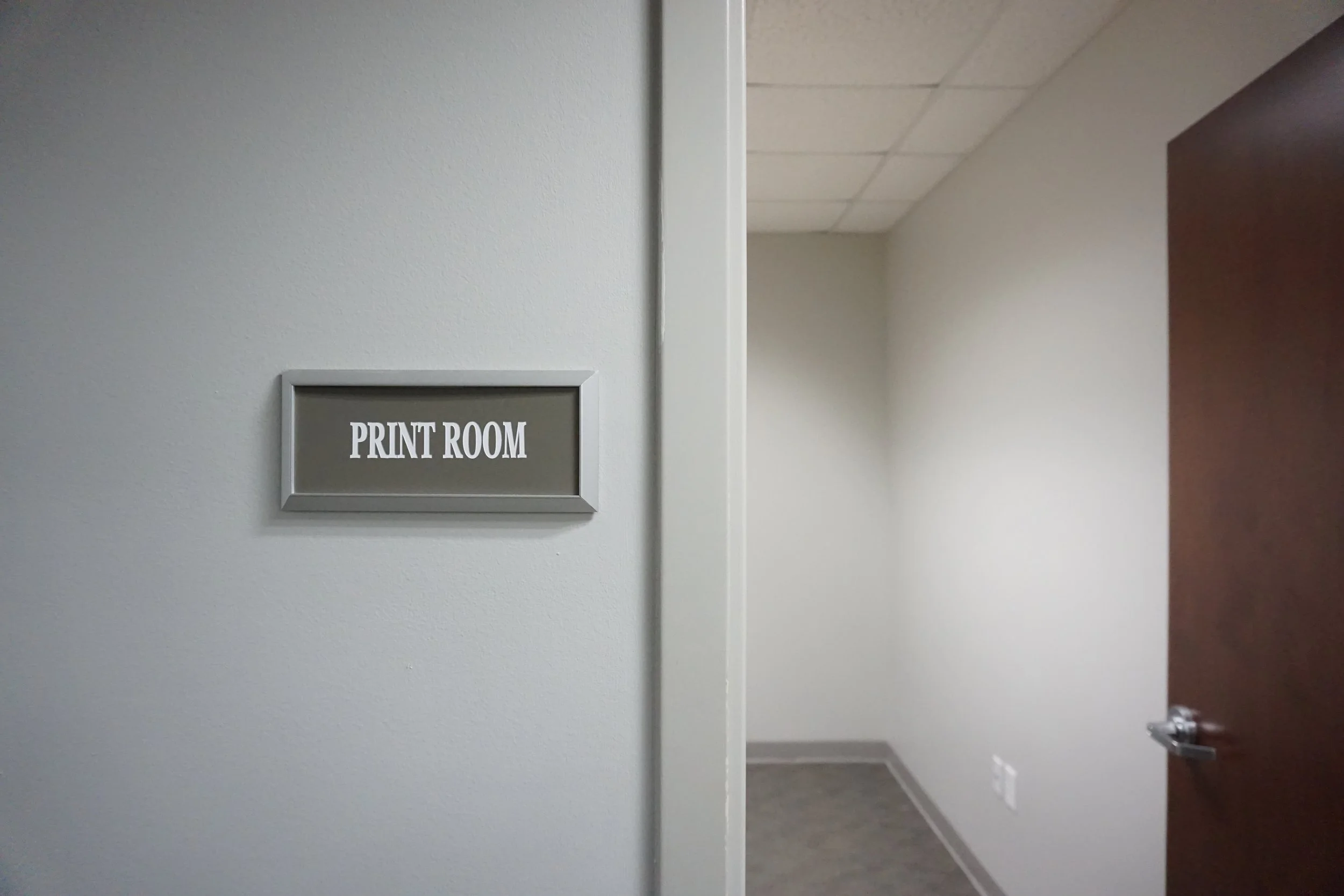 Image of a door with a sign that says 'PRINT ROOM' and an empty room with plain walls and a ceiling.