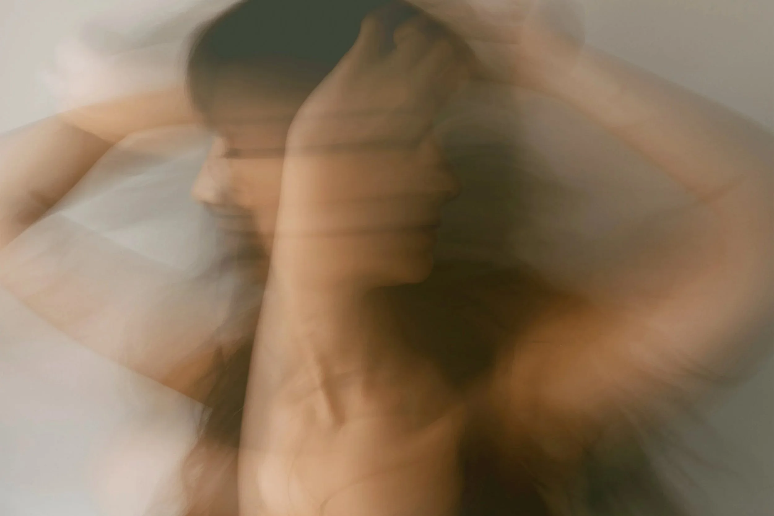 A blurred, overlapping image of a woman with dark hair, dancing with her hands on her head.