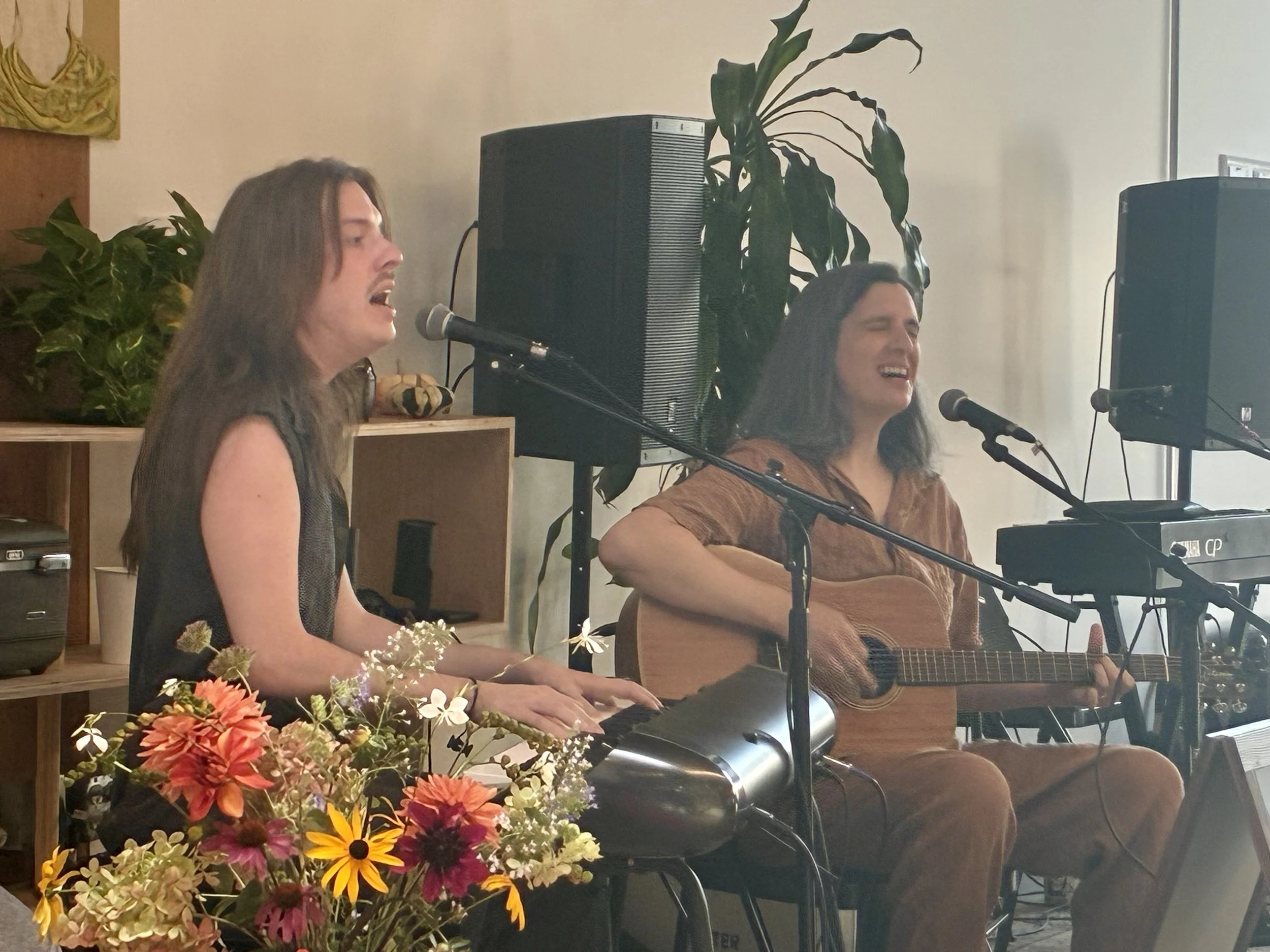 A sidelong image of Sister Sigh performing with a vase of flowers in the foreground