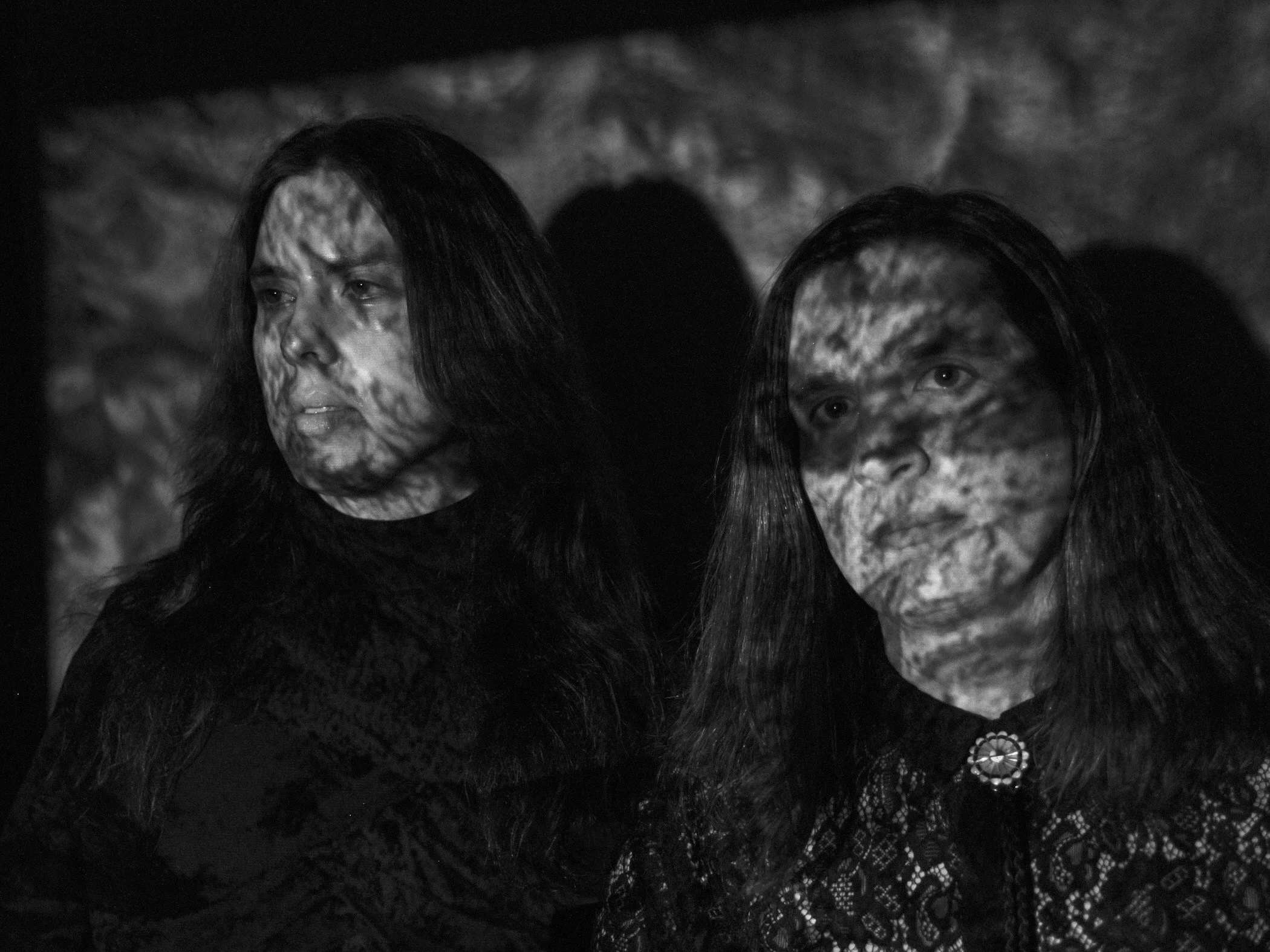 A black-and-white image of Sister Sigh with an image projected onto them.