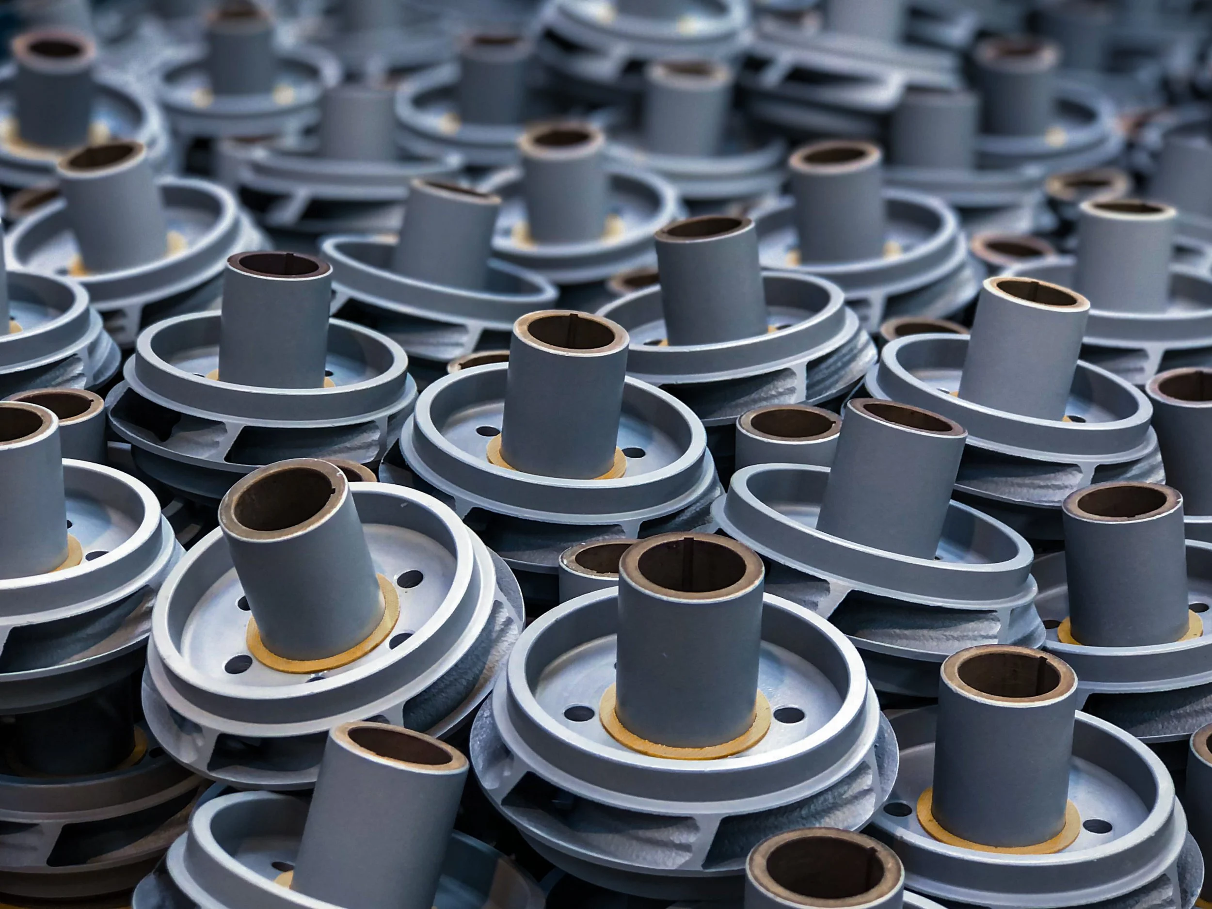 A large pile of metal parts with cylindrical protrusions, arranged haphazardly.