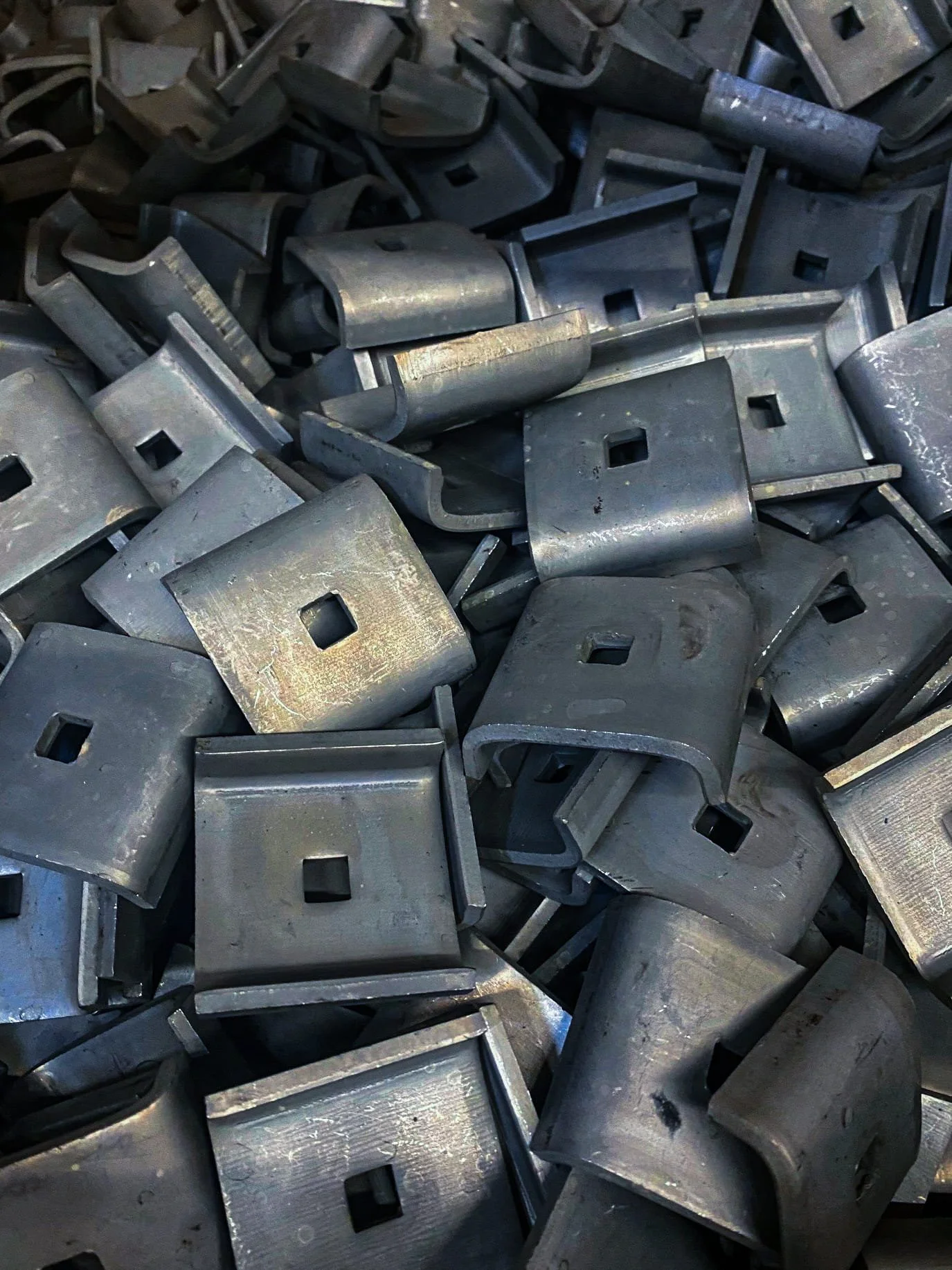 Pile of metallic square brackets that have had boronizing heat treatment.