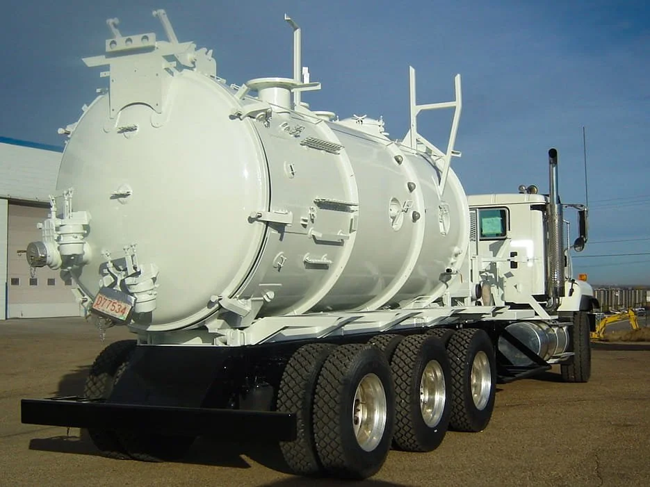 A large white cylindrical vacuum tanker truck with a new white coat of protective coating, located in Edmonton, Alberta.