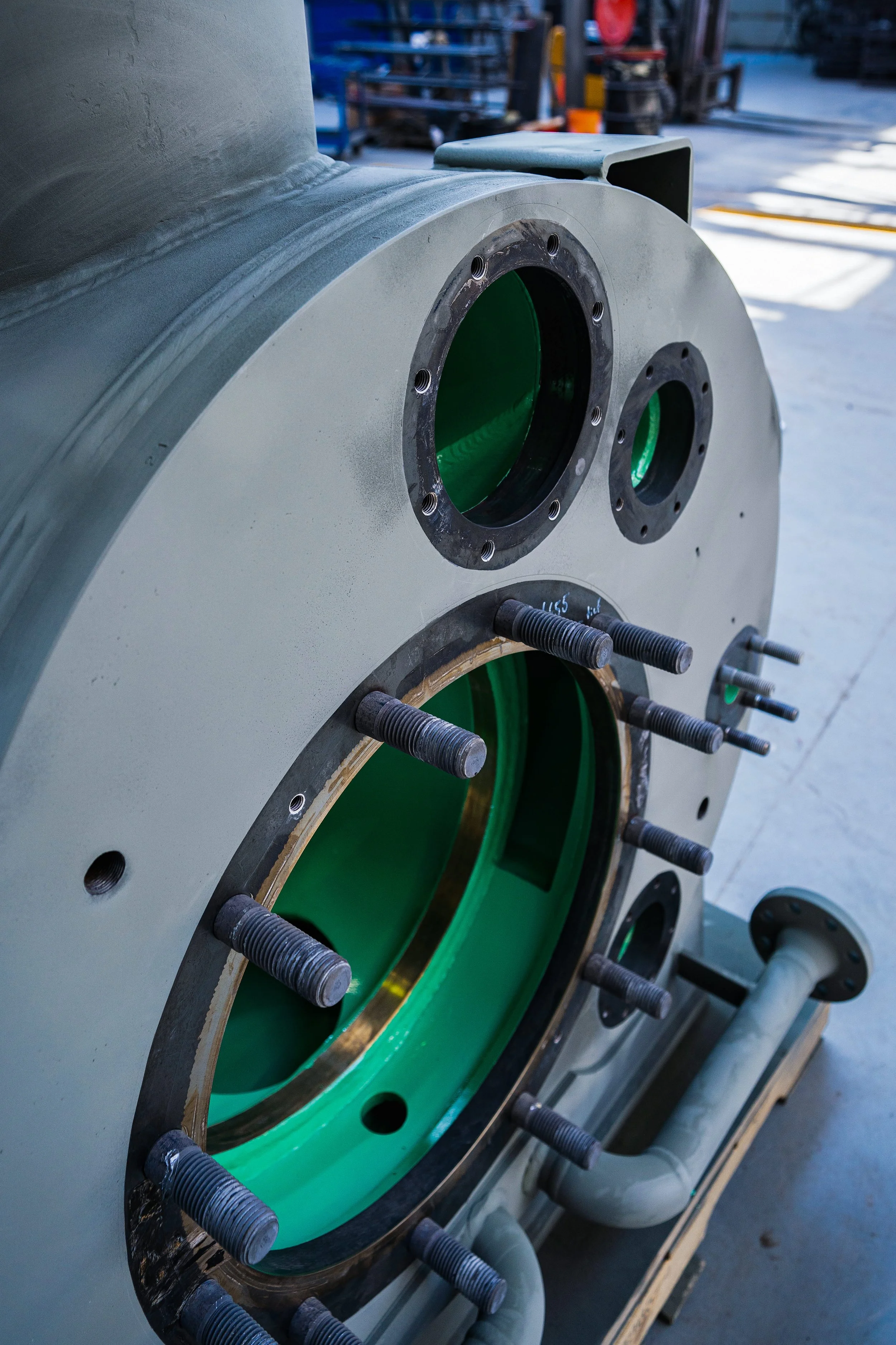 Close-up of a large industrial mechanical component showing Fusion Bond Epoxy coating, situated in a workshop or manufacturing environment.