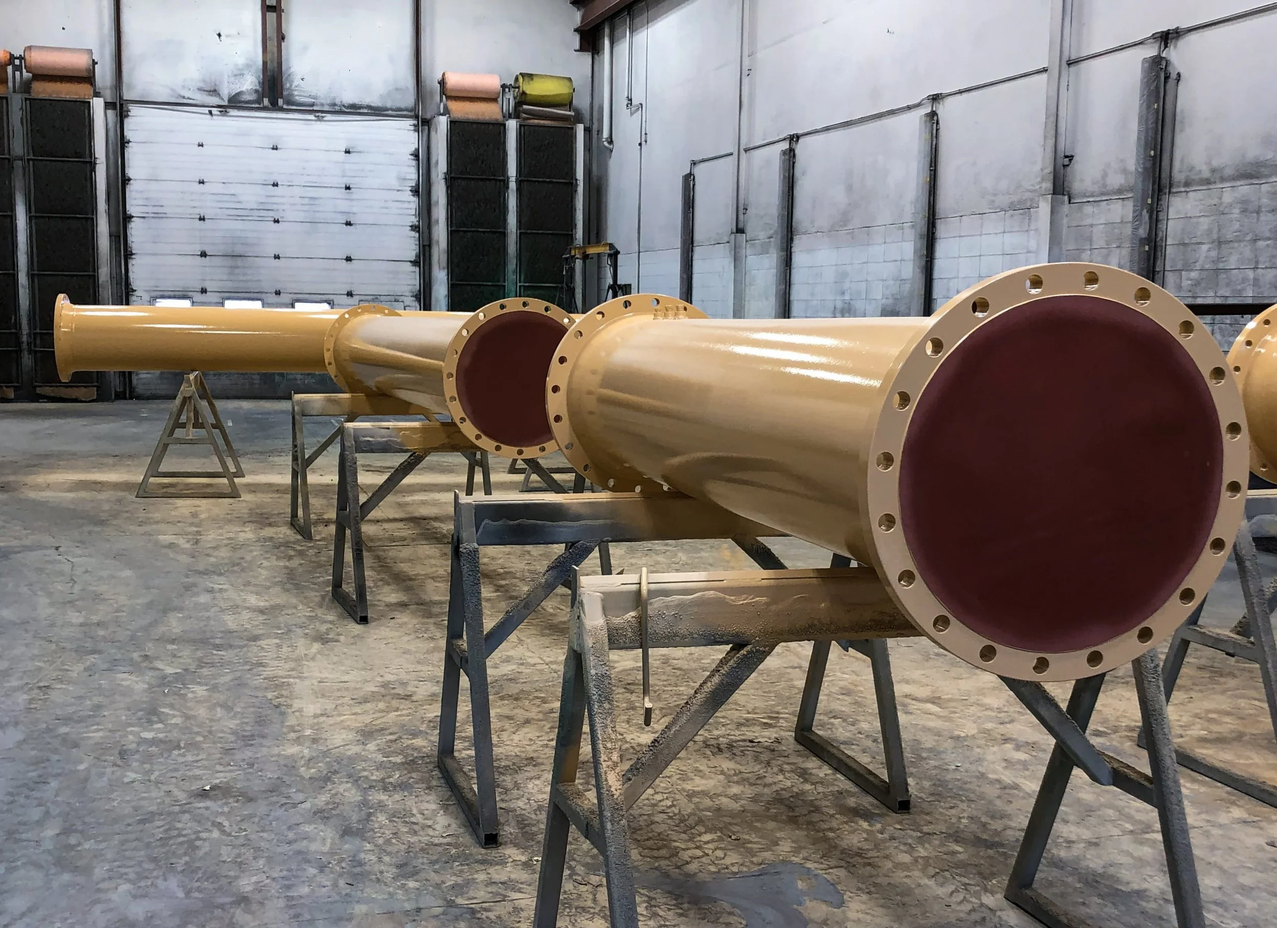A large yellow industrial pipe with flanged ends with an alykd primer paint system from Custom Coatings International