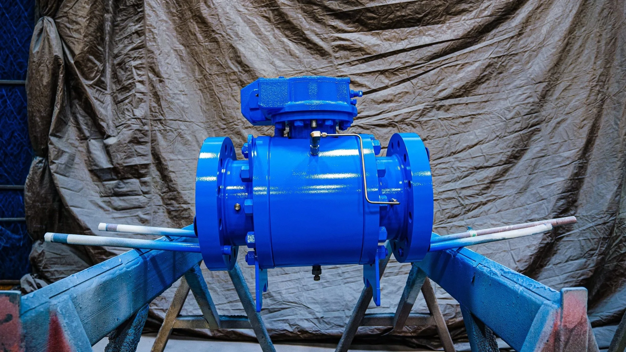 A large, blue industrial valve mounted on a metal stand showcasing Custom Coatings International's industrial painting
