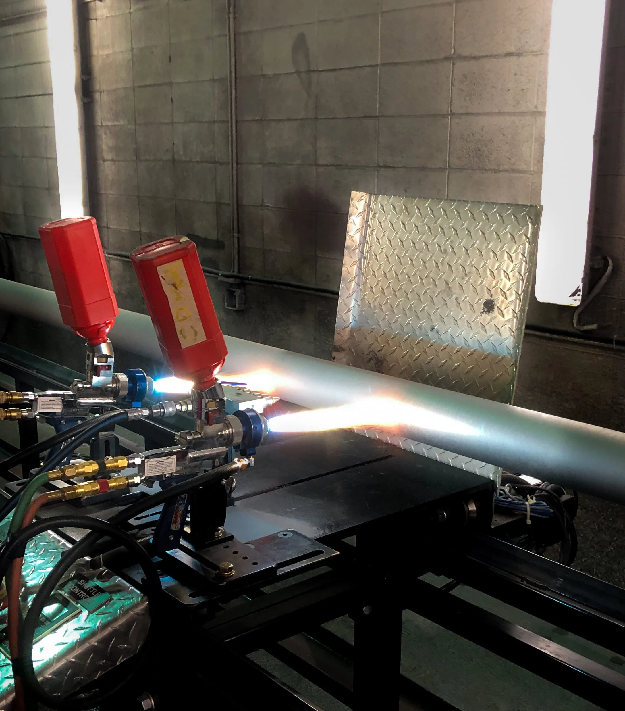 A metal pipe is being coated with thermal/ combustion spray in the Custom Coatings International shop in Leduc, Alberta.