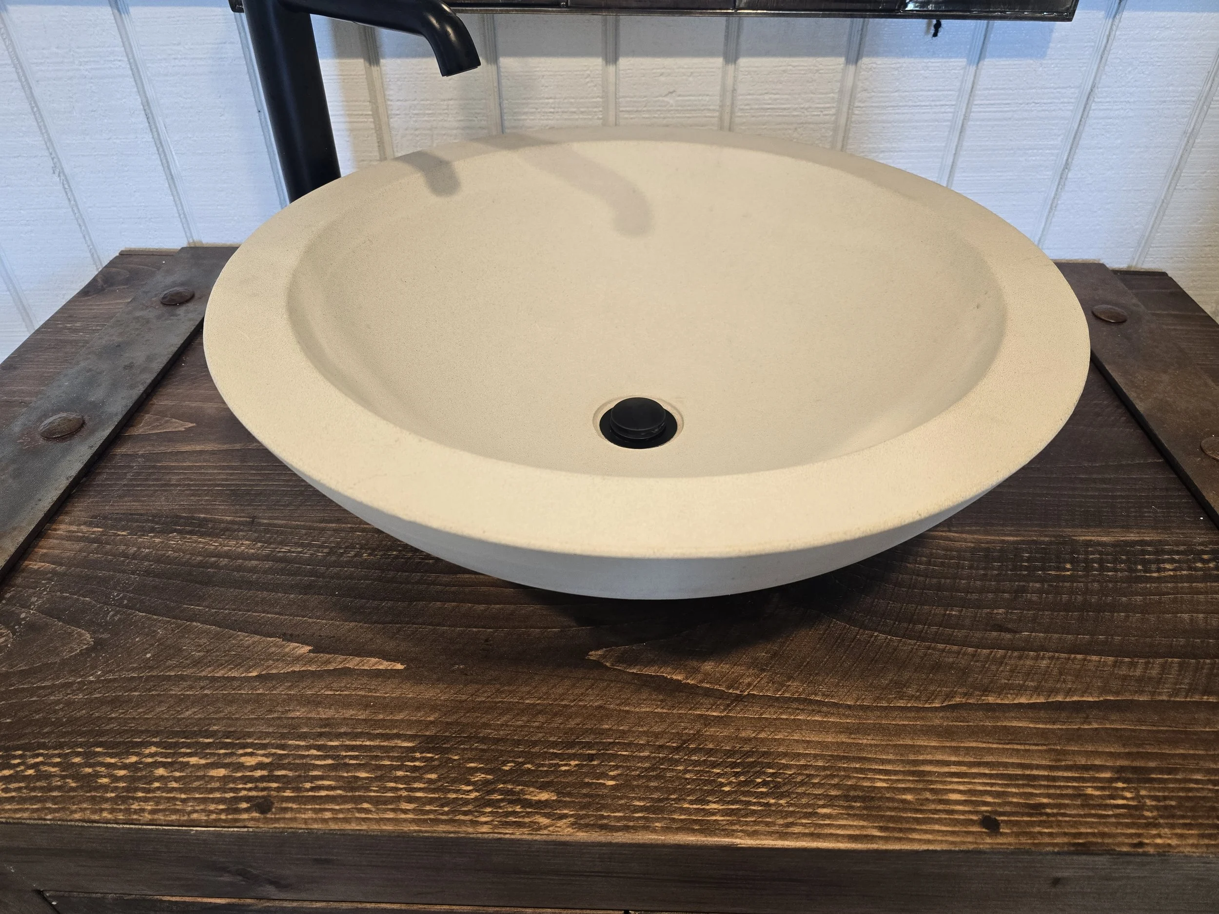 Round concrete bowl vessel on a wood countertop