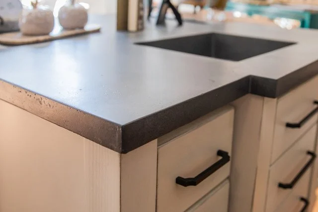Close-up of a kitchen countertop with a built-in sink, showing white cabinets with black handles underneath.