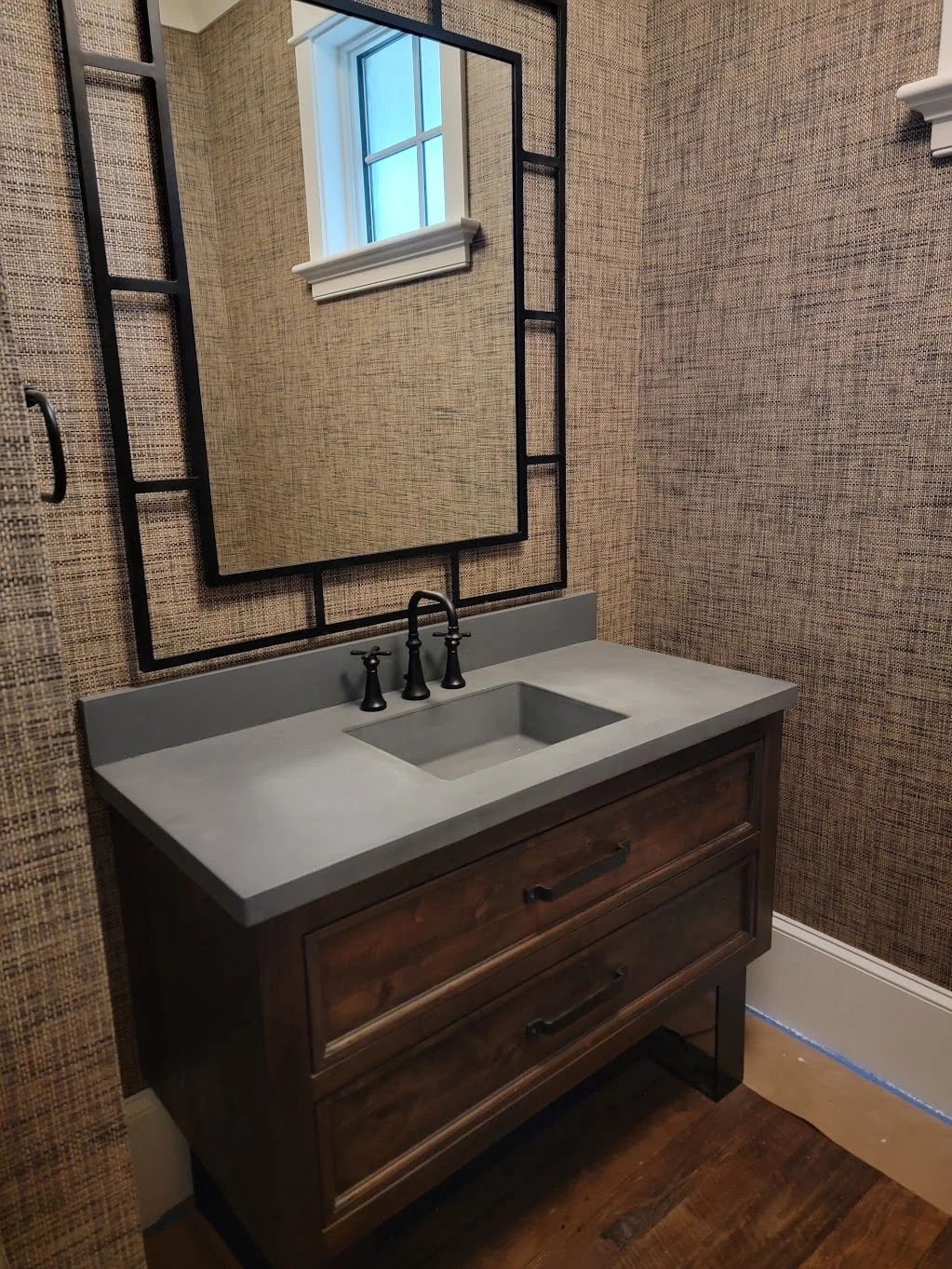 Gray concrete integral sink with matching backsplash installed on a wood vanity