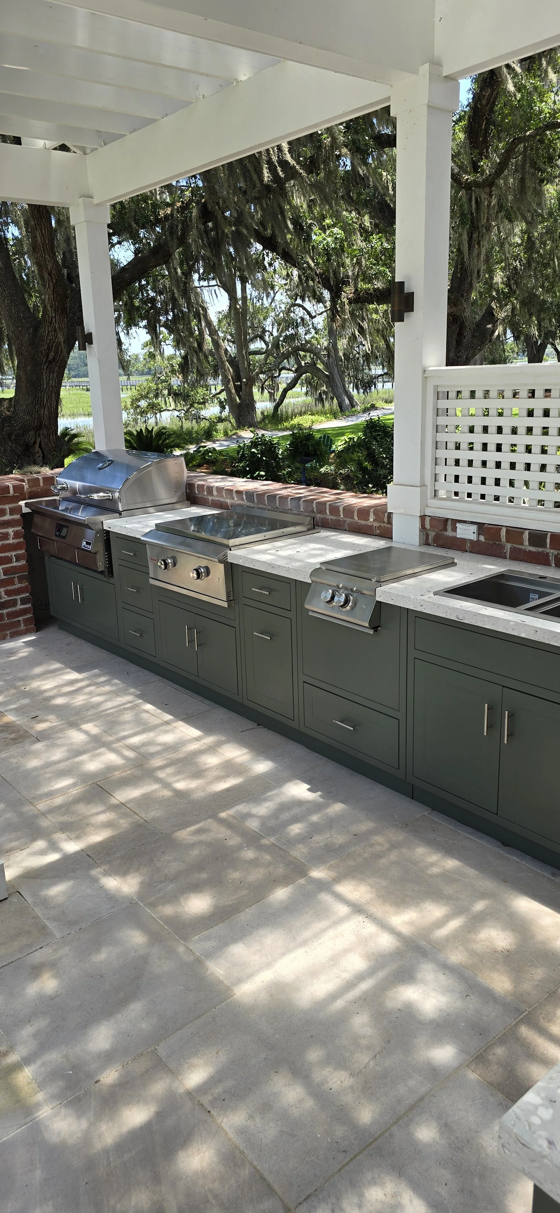 Grill and preparation area with concrete countertops along a covered outdoor kitchen