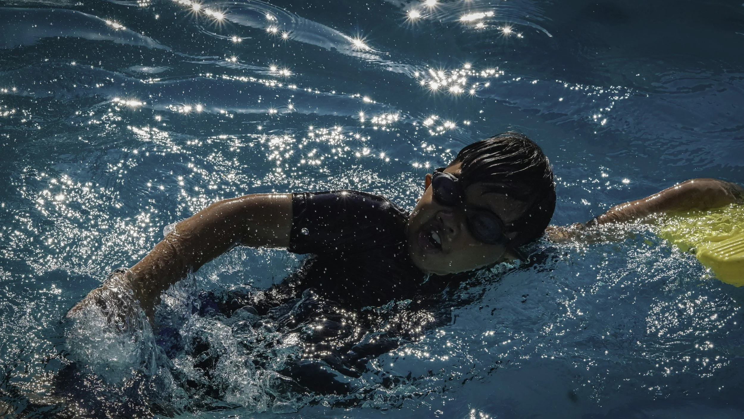 Ein Kind mit Schwimmflossen und Schwimmbrille beim Schwimmen im Pool.