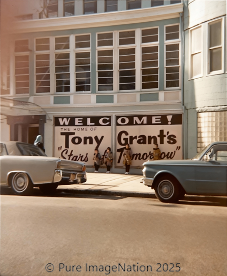 A storefront with a welcome sign for Tony Grant. Vehicles from the 1950s are parked on the street in front of the building.