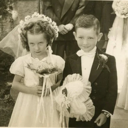 Young flower girl and ring bearer pose in a black and white picture from the 1950s.