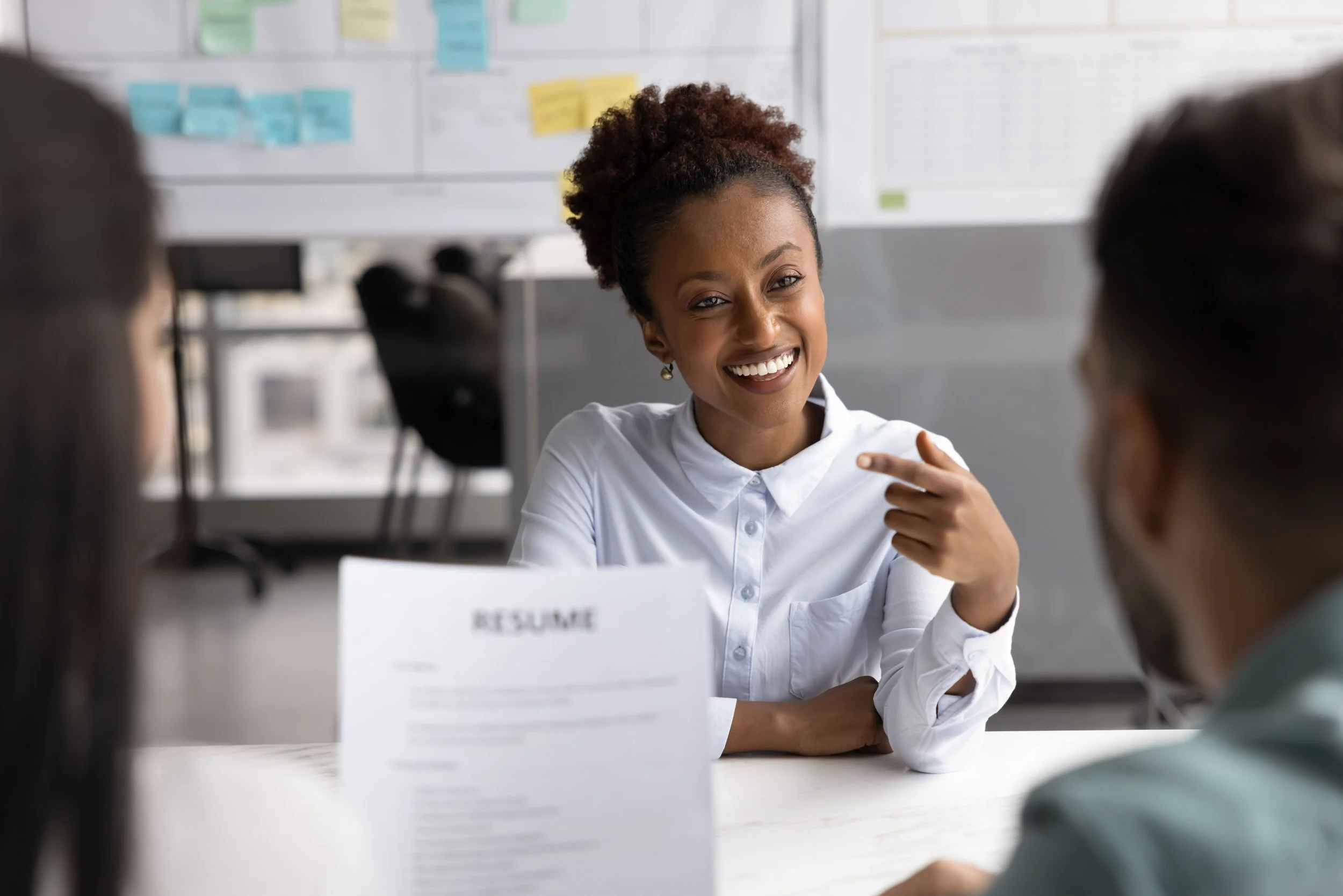 A woman smiling while talking on her cell phone and holding a resume.