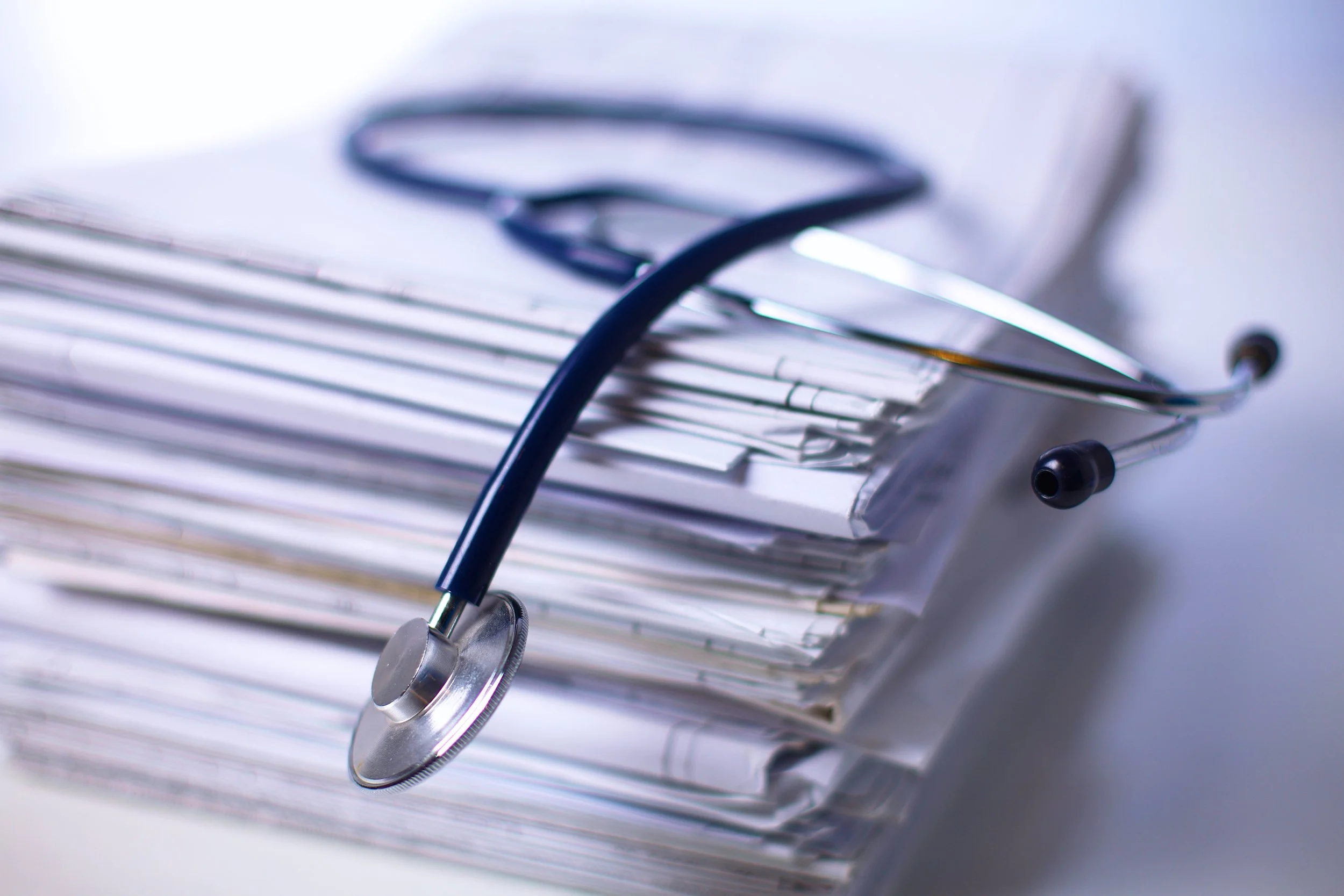 Three people in a professional setting look at documents and a laptop, smiling and engaged in a discussion.