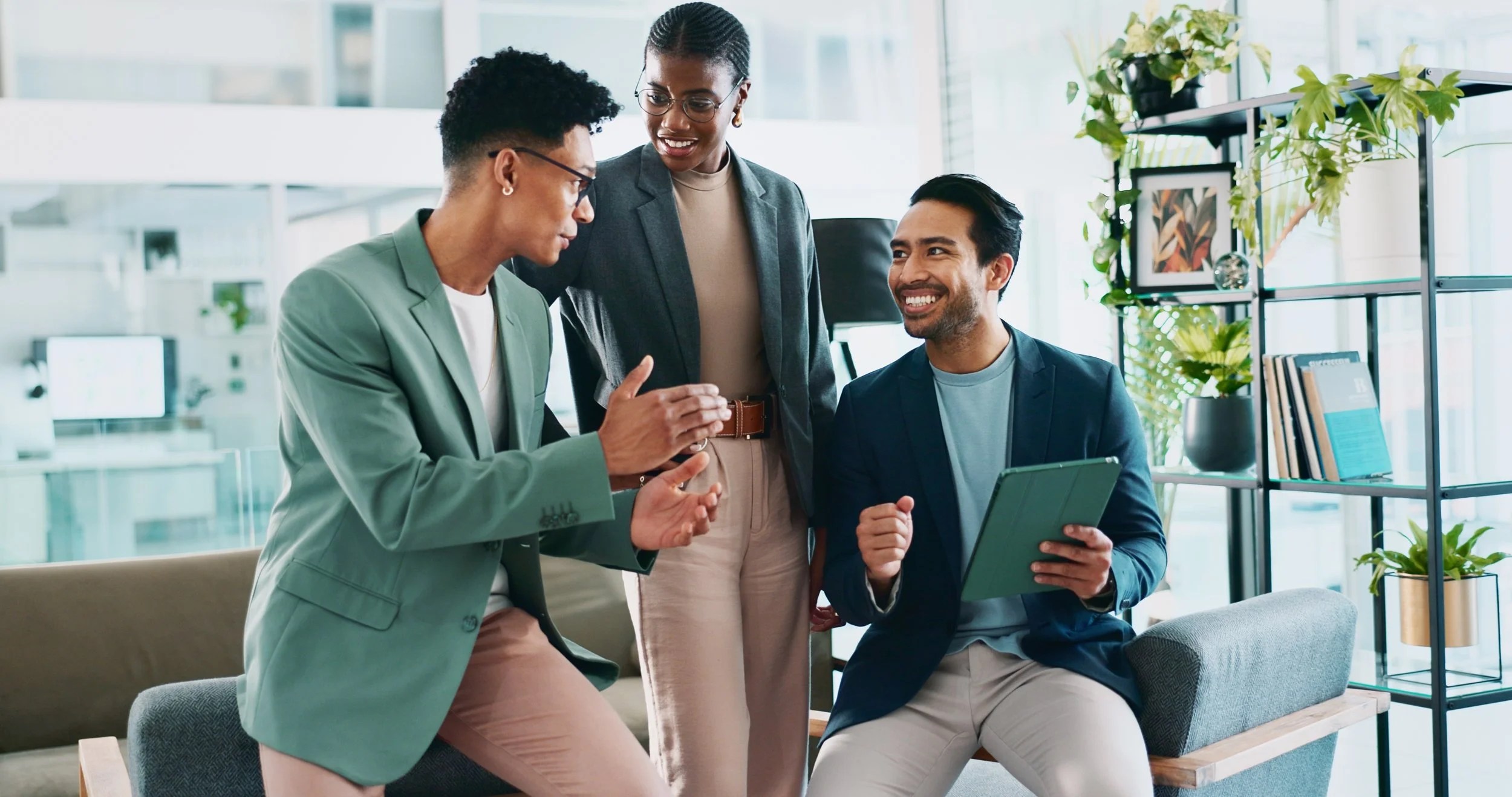 A woman with short curly hair smiling and shaking hands with a man in an office setting.